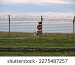 Airport security perimeter fencing system with razor wire with SRA security restricted area stop sign and airplanes behind