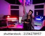 Beautiful stylish girl sound engineer in a recording studio with neon lights in a cap and glasses