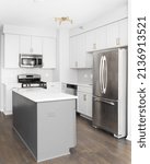 Small photo of BERWYN, IL, USA - AUGUST 17, 2021: A kitchen with white cabinets, a grey island, stainless steel appliances, hardwood floors, and subway tile backsplash.