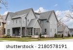 Small photo of BARRINGTON, IL, USA - APRIL 20, 2022: A large grey modern farmhouse with a covered front porch, large windows, and board and batten siding.