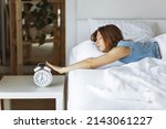 Woman sleep on the bed turns off the alarm clock wake up at the morning, Selective focus.Young woman reaching to turn off alarm clock ,early morning