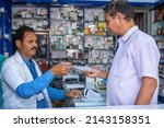Small photo of Customer asking medicine to pharmacist by showing doctor proscription at pharma retail store - concept of small business, customer service and communication