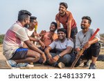 Cricket players discussing with talking each other after playing sports while sitting on playground - concept of friendship, taking break and communication