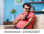Small photo of Elderly senior man checking glucose level by tapping smartphone to monitoring sensor at home - concept of health care, technology and mdicare.