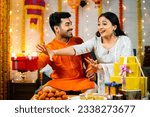 Playful Indian brother playing with sister by not giving gift box during raksha bandhan festival - concept of festival celebration, relationship bonding and togetherness.