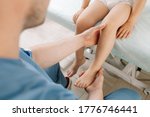 Small photo of A child as prescribed by a doctor with an osteopathic pediatrician. Examination and correction of the legs. The doctor holds the child foot in his arms. In the clinic.