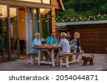 Small photo of Happy family eating together outdoors. Smiling generation family sitting at dining table during dinner. Happy cheerful family enjoying meal together in garden.