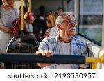 Small photo of An elderly man is in a public transport bus sitting and looking through the window