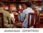 Small photo of A young adult woman is standing and talking in a group mental health session with her peers.