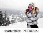 Young woman winter portrait. Winter fashion model with ski suit and goggles. Attractive young woman in wintertime outdoor. Mountains, white snow in magic winter day.
