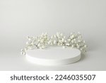 Empty white round podium and gypsophila flowers on light grey background. Showcase for product presentation. Mockup for beauty cosmetic advertising. Minimal still life concept. Copy space, front view.