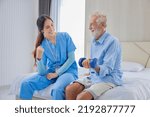 Small photo of Hospice nurse or professional caregiver is helping Caucasian man in bed to exercising muscle strength in pension retirement center for home care rehabilitation and longevity post recovery process