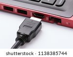 HDMI cable near the HDMI port of the modern red laptop on a white background
