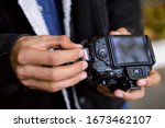 Photographer hand holds Memory card - Flash card near professional DSLR camera. Male photographer ready to insert memory card to his photo camera