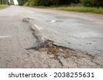 Small photo of Road in terrible condition due to ignoring weight limit and driving very heavy truks. Asphalt road all in inflows and holes