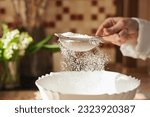 Small photo of Girl sieving flour to the plate for cooking tasty and airy bread. Wife using sieve for flour in cooking