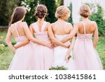 full-length three bridesmaids in powder dresses transformers and hug a bride in a white dress with a wedding bouquet in her hand on a green lawn