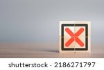 Small photo of Red Cross mark, x, Wrong mark sign, Rejection sign in wooden cube stack. Concept of negative decision making or choice of vote with copy space for background or text.