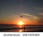  beach sunset with little boy playing while little airplane flies over cessna         