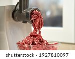  Side view of a meat grinder and minced meat falling into a glass bowl. Selective focus.                              
