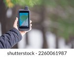 Small photo of Tourist navigator in a shockproof rubberized case in a man's hand on a blurry background of a winter forest. On the screen is a map of the area and waypoints.