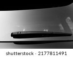Small photo of close up of back wiper on black new car windows. A windscreen wiper or windshield wiper is a device used to remove rain, snow, ice and debris from a windscreen or windshield
