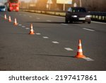 Small photo of A row of traffic orange striped cones on the road. sunlight. These objects are temporary traffic control devices for directing and avoiding sections of the road being repaired or diverting traffic