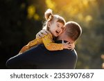 Joyful dad hugs his little smiling daughter. Single daddy and child have fun, laugh and enjoy nature outdoors at autumn park. Concept of parental care and happy carefree childhood. Happy fathers day.