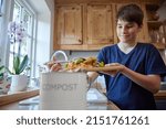 Small photo of Boy In Kitchen Making Compost Scraping Vegetable Leftovers Into Bin