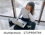 attractive girl working with laptop and things in airport terminal or office on floor. travel atmosphere or alternative work atmosphere. concept of alternative workplace, technology and waiting.