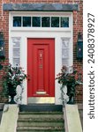 Small photo of A bright red front door with cream trim and a transom with front steps on a red brick house building.