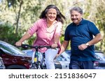 Healthy and fit old  Indian couple riding bicycle in the park summer, active old age people and lifestyle. Elderly woman learn to ride cycle with man. retired people having enjoy life. 