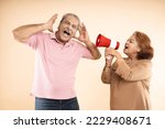 Small photo of Senior indian woman scream or shouting at man in megaphone isolated on beige background. announce discounts sale. Asian wife tease husband.