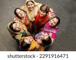 Group of happy young traditional indian women wearing colorful sari looking up and embracing each other like a team. Rural india. women empowerment. World women
