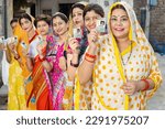 Group of happy traditional indian women standing in queue showing voter card id to cast vote at polling station. Election in india.