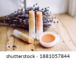 Make homemade natural organic ingredients lip balm. Handmade lip balm and lipstick inside container on natural wooden background and lavender for decoration.