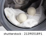 Small photo of Using wool dryer balls for more soft clothes while tumble drying in washing machine concept. Discharge static electricity and shorten drying time, save energy.