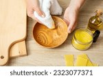 Small photo of Woman hands apply homemade beeswax wood treatment polish to restore natural wood bowl color. Beeswax, olive oil and essential oil, soft cloth and mixture in glass jar. Polishing wood.