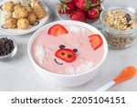 Fun food for kids - smoothie-bowl in shape funny piglet, with strawberries, granola, chocolate and crispy balls on gray background