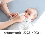 Small photo of Mother using baby nasal aspirator mucus nose suction. Mother cleaning baby nose. Baby watching to camera.