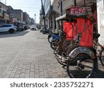 Small photo of Bandung, West Java, Indonesia - July 10, 2023. A becak or pedicab on a roadside in Bandung City with a paved road. Becak's are used in Bandung and are one of the cheapest ways of getting around.