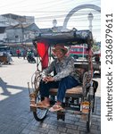 Small photo of Bandung, West Java, Indonesia - July 10, 2023. A smiling becak or pedicab driver in Bandung City. Becak's are common in Bandung and are one of the cheapest ways of getting around the city.