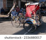 Small photo of Bandung, West Java, Indonesia - July 10, 2023. Drivers with their becak pedicabs sitting on a roadside in Bandung City. Becak's are used in Bandung and are one of the cheapest ways of getting around.