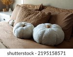 Small photo of Stuffed, white DIY pumpkins made of Sherpa fabric on a warm brown bed set