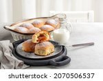 Small photo of Breakfast time: sweet bread rolls with jam filling powdered with sugar. Homemade. Jag of milk. Light table.