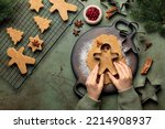 Children's hands cutting shapes and making Christmas cookies. Gingerbread man. Raw batter flavored with ginger, hazelnut, nutmeg, and cinnamon. Christmas and New Year food. Top view of kitchen table.