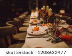 Thanksgiving table setting with autumn decorations, pumpkins, glasses and plates. Holidays, catering and hospitality concept.