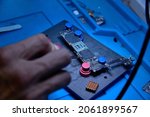 Small photo of Hands of cellphone technology device maintenance engineer work on chipset pins of removed microprocessor from smartphone motherboard with tweezers. Close-up macro photo, Selective focus