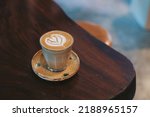 Small photo of A cup of coffee latte art Rosetta on wooden table.