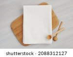 White blank cotton kitchen towel mockup for design presentation, wooden spoons and cutting board.